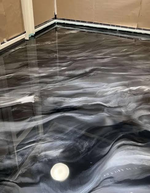 Détail d'un sol en résine époxy marbré noir et argent, finition brillante